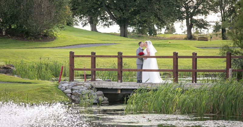 Bride and Groom on Bridge by Lake on Golf Course